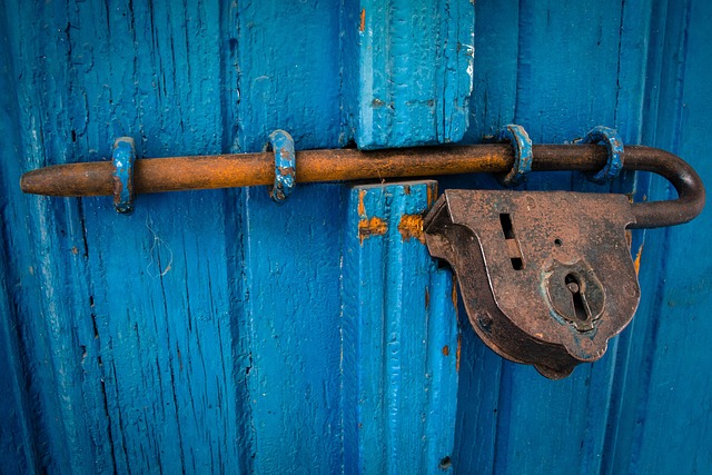 antique rusted badlock on a weatherd vibrant blue wood door